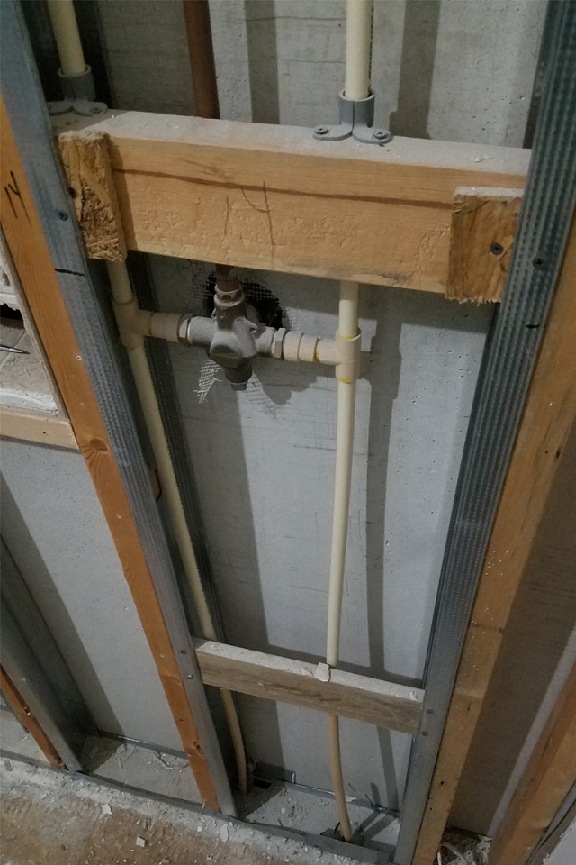 Plumbing and insulation exposed behind the studio wall